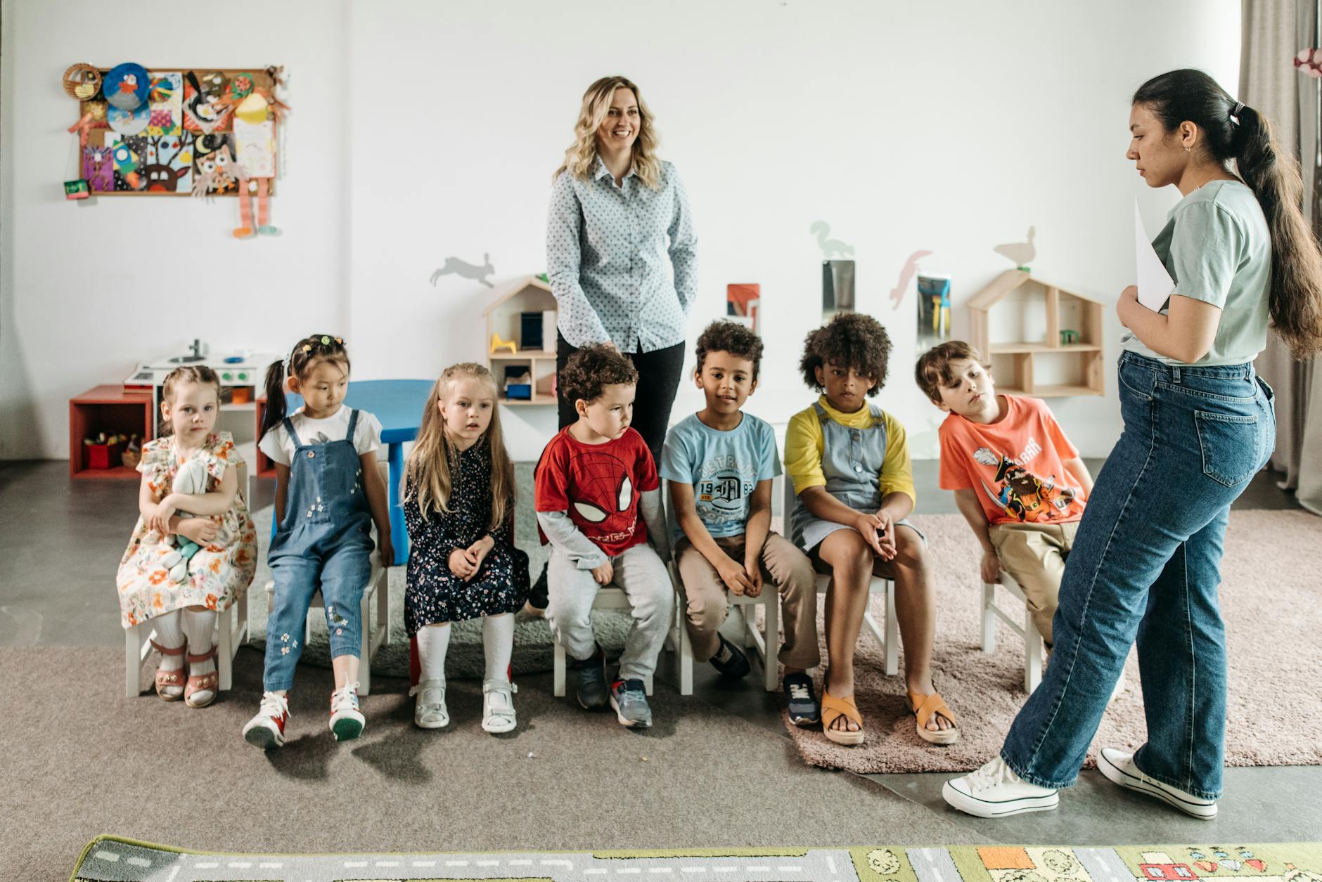 group of children sitting on white chairs